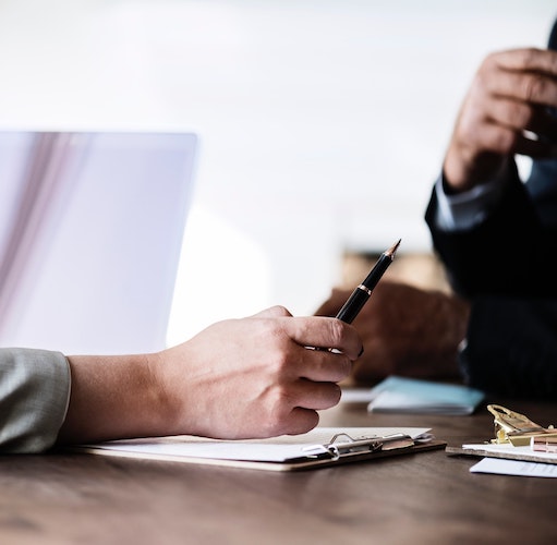 A photo of two people having a discussion at a desk in an office.